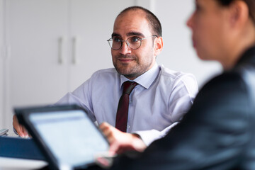 business meeting 4 people with laptops ipad tablet folios pens and folios in bright office with...