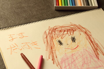 子供がクレヨンでスケッチブックに描いた母親の絵