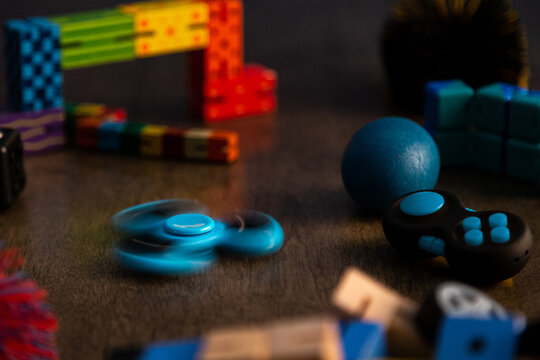 Spinning blue fidget spinner surrounded by other fidget toys for children. 