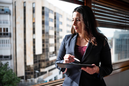 Woman At Large Bright Window In Office With Ipad Tablet Taking Notes Doing Business Smiling Happy