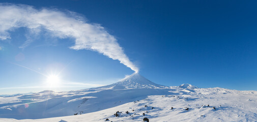 Winter volcanic landscape, panoramic view of eruption active volcano plume gas, ash from crater in...