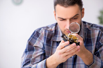 Young male watchmaker working in the workshop