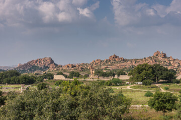 Fototapeta na wymiar Hampi, Karnataka, India - November 4, 2013: Royal Enclosure. Wide shot of the scenery around and above with the Mohammadan Watch Tower about in center. Rocky hills under blue sky. Green vegetation.