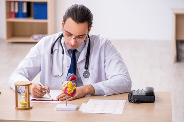 Young male doctor cardiologist in time management concept