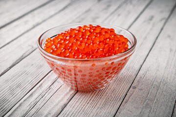 Fresh salted red salmon caviar with a silver spoon with eggs of ideal spherical shape in a transparent bowl. Premium quality product.