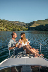 Fototapeta premium Young couple on a yacht holding two glasses of wine