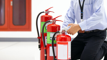 Office man checking the handle of the red fire extinguishers tank in the building concepts of prevent case for emergency and safety rescue and fire training.