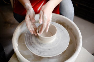Female hands crafting a pottery cup on a potter's wheel. Handmade and crafting concept. Top horizontal view copyspace.