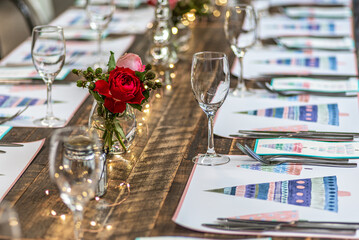 A long table set up for Christmas dinner with placemats, cutlery, glasses and flowers