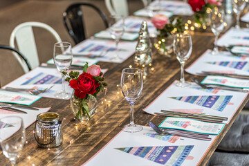 A long table set up for Christmas dinner with placemats, cutlery, glasses and flowers