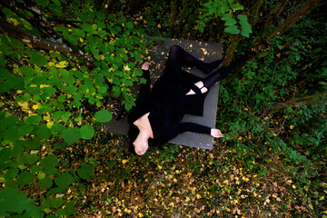 sexy young brunette woman, lying dead in a black dress on square table in autumn forest, copy space
