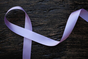 Top view of lavender or light purple orchid color ribbon on dark wooden background. General and...