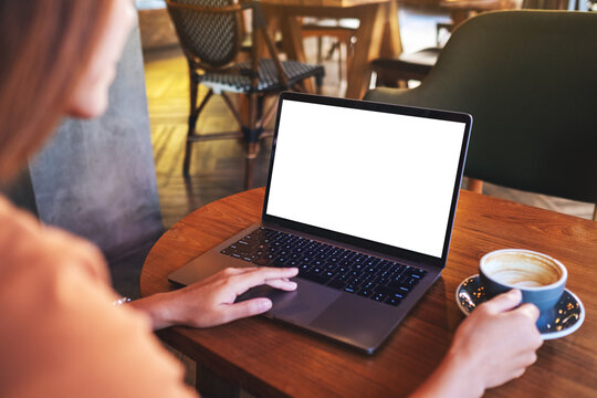 Mockup image of a woman touching on laptop computer touchpad with blank white desktop screen while drinking coffee