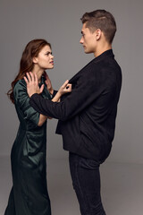 woman holding a man behind a jacket on a gray background indignant look stress conflict