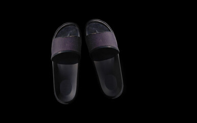Pair of black indoor slippers isolated on black, copy space for text, shoe texture, background and summer concept.