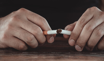 Closeup of a male hand holding cigarette and breaking a cigarette. Smoking cessation concept