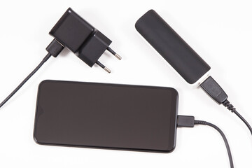 External powerbank or electric charger charging empty battery of smartphone or mobile phone