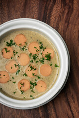 German traditional KARTOFFELSUPPE potato and sausage soup on wood table