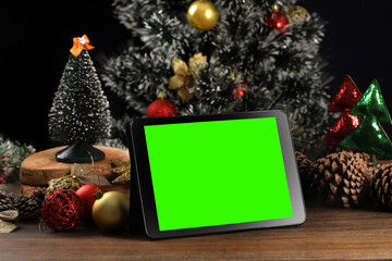 Tablet on black background with Christmas decoration and wooden table