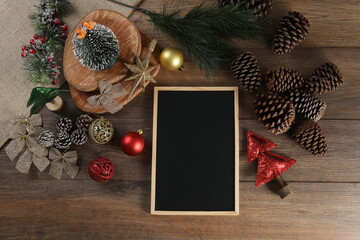 Top view of frame with black background and Christmas decoration on wooden table.