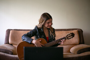 Young woman takes online classes to learn to play acoustic guitar