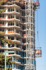 Long hoisting tower crane in construction new apartment building process. White Rock, British Columbia.