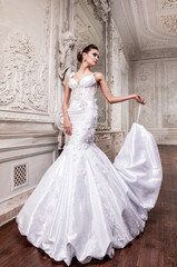 Beautiful bride in a white wedding dress in a light old classic interior