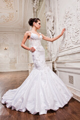 Fototapeta premium Beautiful bride in a white wedding dress in a light old classic interior