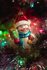 Obraz premium Defocused photo of vintage christmas toy on a fir tree with blurry lights. Soft watercolor texture of New Year decoration. Cozy home, family holiday, Christmas background.