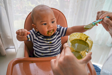 An asian kid boy in high chair or feeding table eating healthy food. Concept of child food, family...