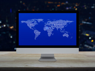 Start up business icon with global words world map on desktop modern computer monitor screen on wooden table over blur colorful night light city tower and skyscraper, Happy new year 2021 global busine