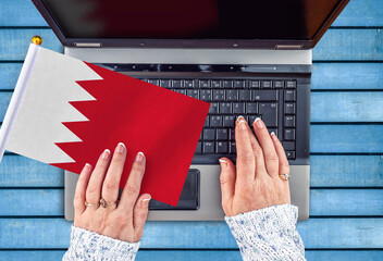 woman hands and flag of Bahrain on computer, laptop keyboard 