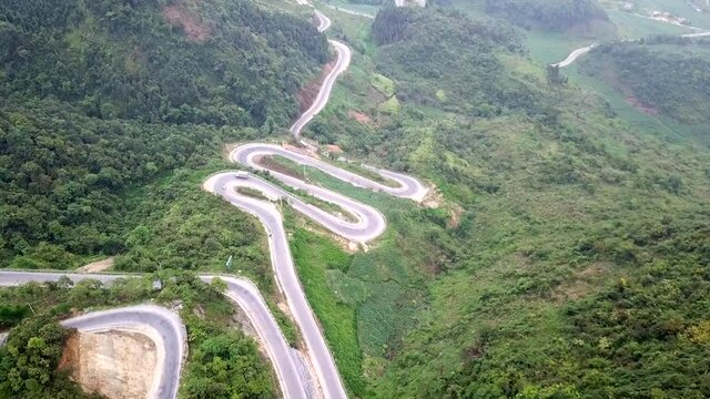 Drone shot of hairpins and a curvy road in Ha Giang Province, Vietnam on Ma Pi Leng Pass. Dangerous road passing through the mountains and rice terraces