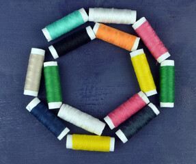 
threads of different colors lie in a circle on a blue background soft focus