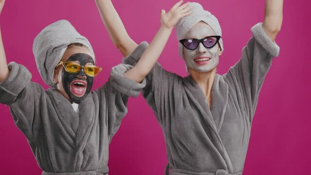 Portrait funny caucasian young couple girl and mother wearing wheet masks and aunglasses performing comical singing and dancing on pink background.