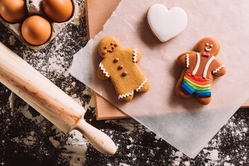 Christmas gay cookies. Lgbt Valentines day party. National diversity. Conceptual bakery love. Colorful gingerbread men with white icing heart figure biscuit on black desk copy space.
