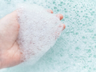 Hand with white foam soap bubbles. Bath time.Handwashing and hygiene concept with copy space. 