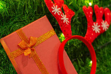 Christmas gift box. Christmas presents in red boxes with Antler headband on Christmas tree background. New Year.
