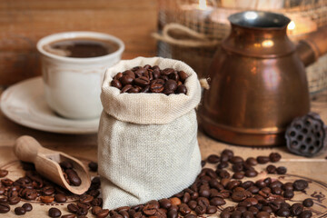 Cup of coffee and jute sack with raw grains on the table.