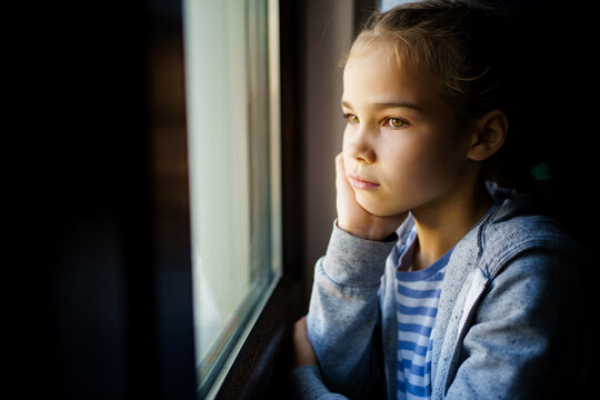 through glass. sad teen girl look out of window outside. 