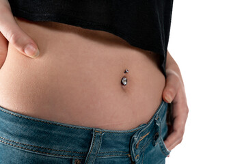 Belly button or navel piercing, of young woman wearing jeans isolated on white.