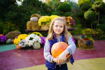Fototapeta premium Funny girl with pumpkin in hands on walk in park on Halloween.