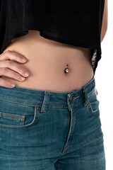 Naklejka premium Belly button or navel piercing, of young woman wearing jeans isolated on white.