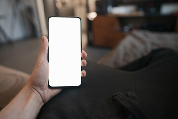 POV photo of man holding smartphone with white screen while sitting on a couch