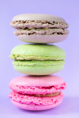 Three french round cookies one on top of each other on purple background. Stack of almond biscuits close up