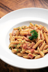 penne amatriciana tomato and ham sauce pasta on wood table
