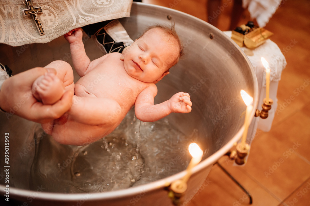 Sticker a child is lowered into the water in a font at a Christian baptism in the church