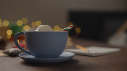 hot chocolate in blue cup in the evening with shopping list for holidays in notepad