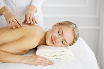 Obraz na płótnie Canvas Beautiful caucasian woman enjoying back massage with closed eyes. Beauty and Spa salon concept