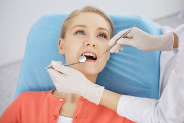 Smiling caucasian woman is being examined by dentist at dental clinic. Healthy teeth and medicine, stomatology concept